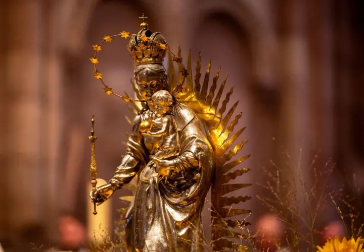 Goldene Statue der Maria mit Kind, gekrönt und von Strahlen umgeben. Die Bedeutung von Maria wird hier durch ihre königliche Darstellung und die Verehrung deutlich.