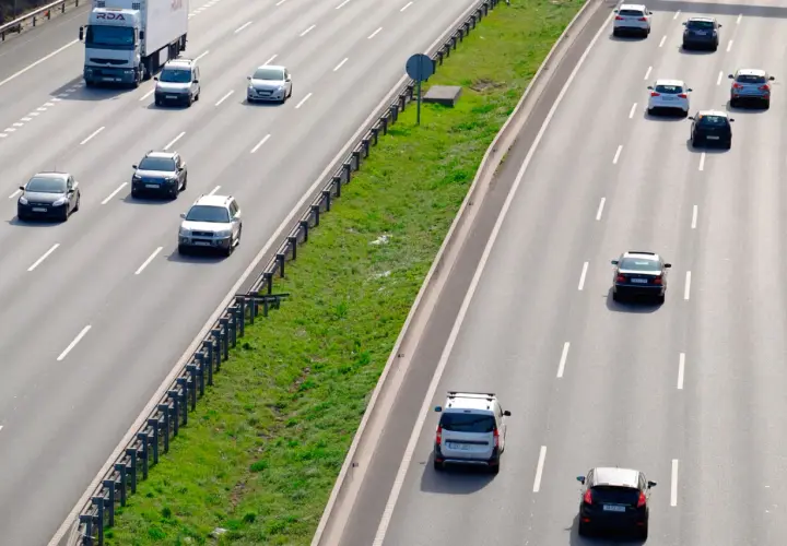 Varios coches circulan por la autopista. Un camión blanco lidera el tráfico. ¿Es correcto este adelantamiento?