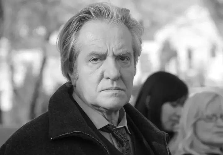 Jerzy Grałek, aktor, w czarnym płaszczu i krawacie, zamyślony.