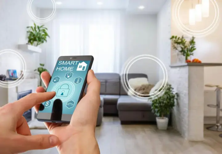 Smart home od czego zacząć? Telefon z aplikacją sterującą domem w nowoczesnym salonie.