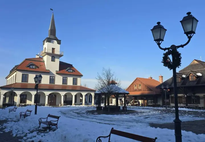 Zimowy dzień w skansenie. Miasteczko galicyjskie z ośnieżonym rynkiem, ratuszem i karczmą.
