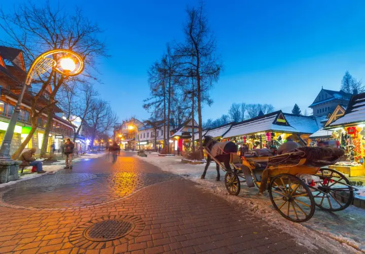 Wieczorny spacer po Krupówkach, gdzie zakopiańskie centrum kultury tętni życiem. Konny zaprzęg i oświetlone kramy tworzą magiczny klimat.