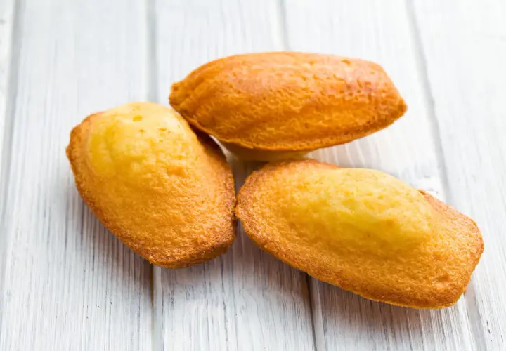 Trois madeleines dorées sur fond de bois clair, parfaites pour une recette de madeleines salées pour apéritif.