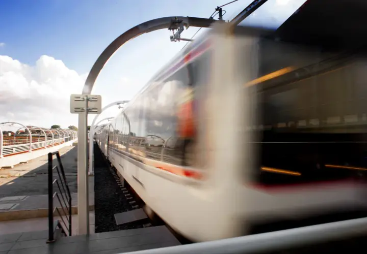 Treno in corsa sulla borghesiana metro c, con riflessi nel cielo e luci interne.