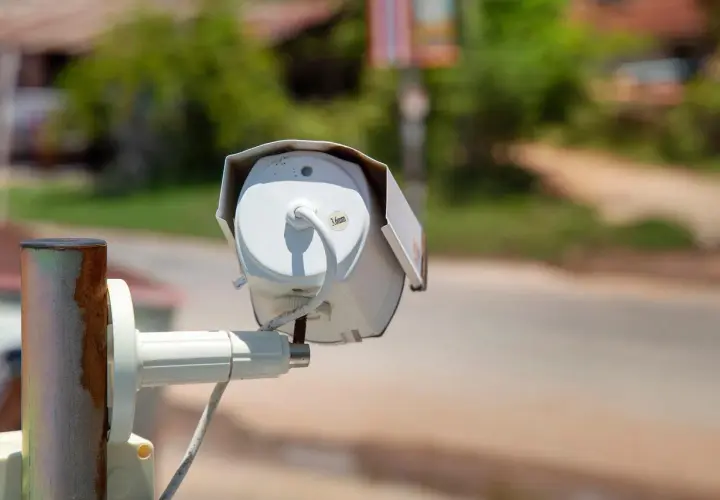 Kamera do monitoringu domu, zamontowana na zardzewiałym słupku, czuwa nad otoczeniem.