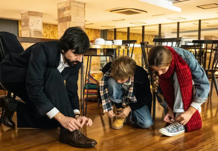 Padre e figli si allacciano le scarpe, un momento di vita quotidiana che merita recensioni positive per la sua semplicità.