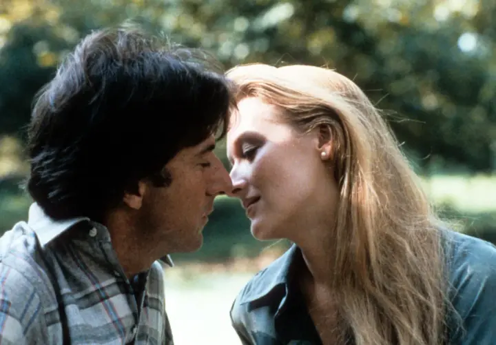 Un tenero momento tra John Cazale e Meryl Streep, i loro volti vicini in un abbraccio intimo.