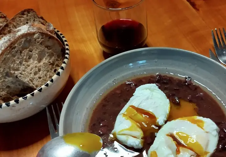 Œufs meurette, un plat d'origine française, servis avec du pain et du vin rouge.
