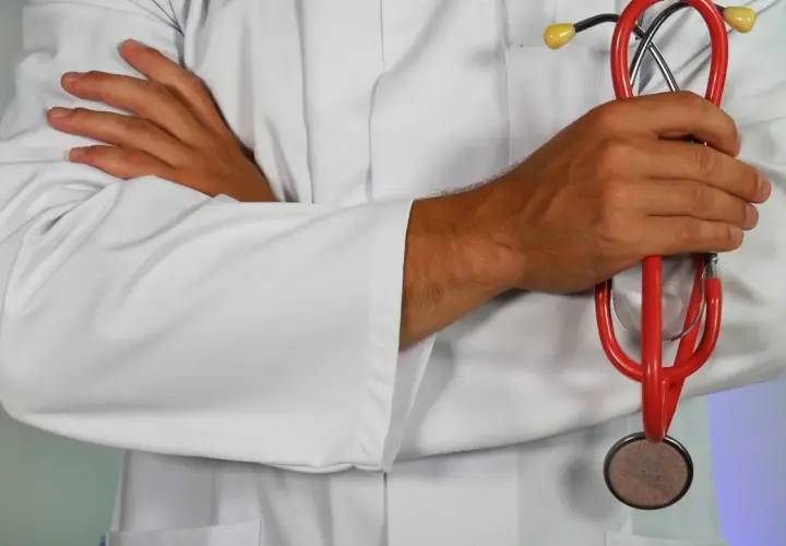 Medico con camice bianco e stetoscopio rosso, pronto ad assistere i pazienti.