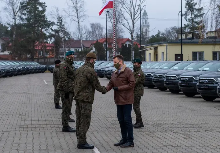 Rangers wojsko odbierają nowe pojazdy. W tle rzędy samochodów i polska flaga.