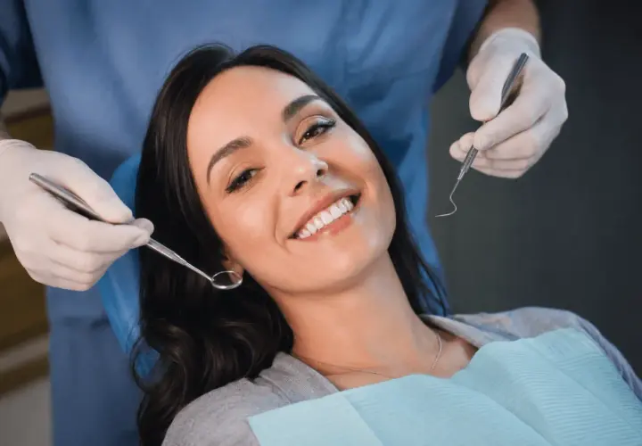 Uśmiechnięta pacjentka u dentysty, która mimo narzędzi nie wykazuje odruch wymiotny.