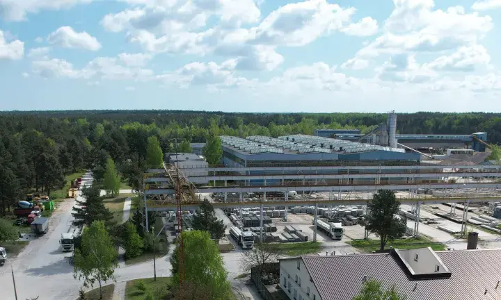 Fabryka domów Bogucin z lotu ptaka. Widok na hale produkcyjne, place składowe z elementami prefabrykowanymi i ciężarówki.