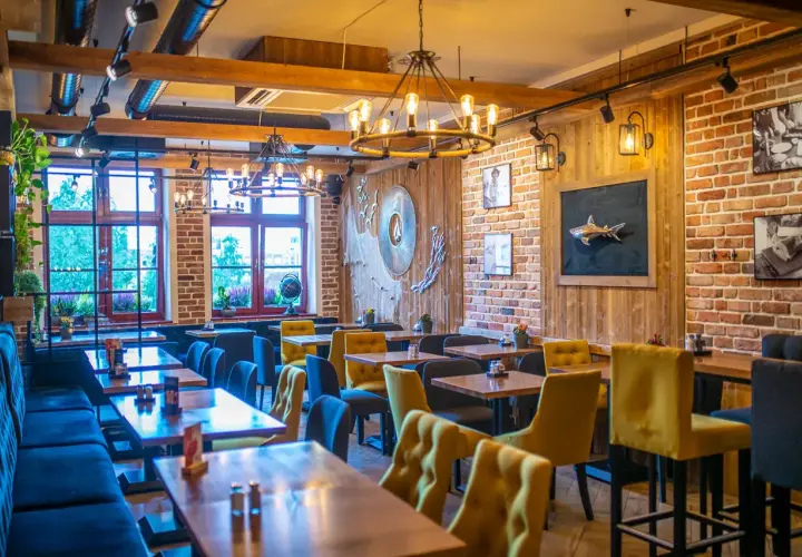 Przytulne wnętrze z ceglanymi ścianami i drewnianymi elementami, idealne na odkrycie najlepszych restauracji w Sopocie.