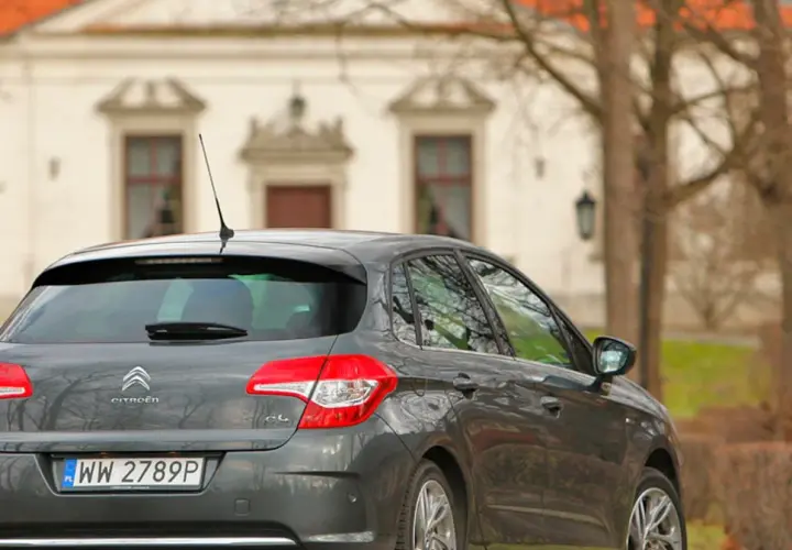 Szary Citroen C4 1.6 HDi zaparkowany przed zabytkowym budynkiem.