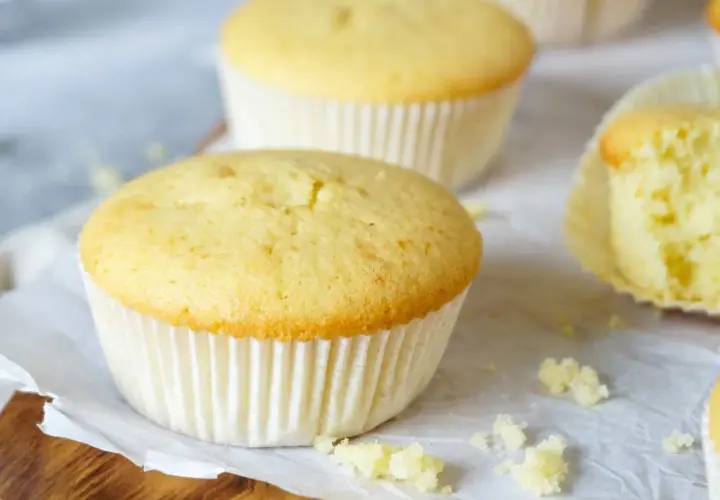 Zarte Muffins, perfekt für das Muffins Grundrezept. Einer ist angeschnitten und zeigt die fluffige Textur.