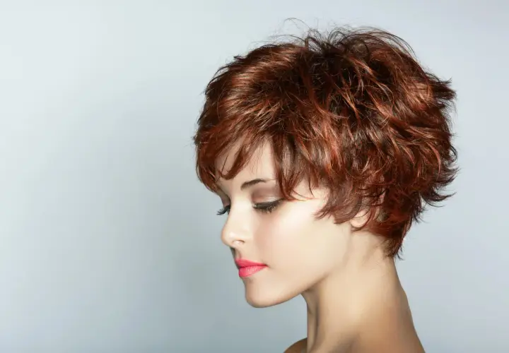 Kobieta z rudymi, potarganymi włosami, prezentująca eleganckie fryzury na krótkie włosy.
