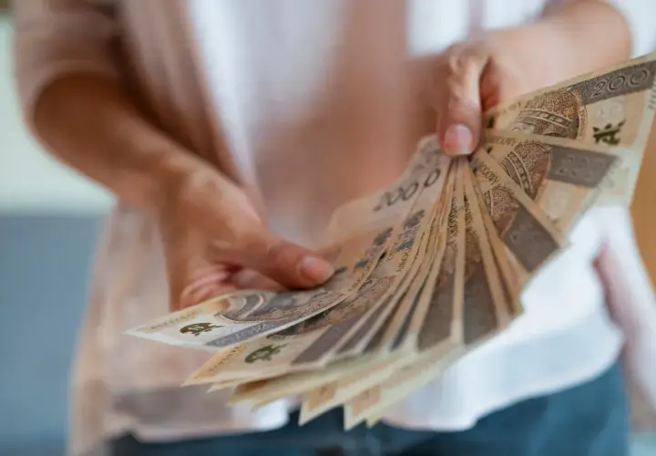 Dłonie trzymają wachlarz banknotów 200 zł. To symbol nagrody jubileuszowej za 40 lat pracy w budżetówce, zasłużone docenienie wieloletniego trudu.