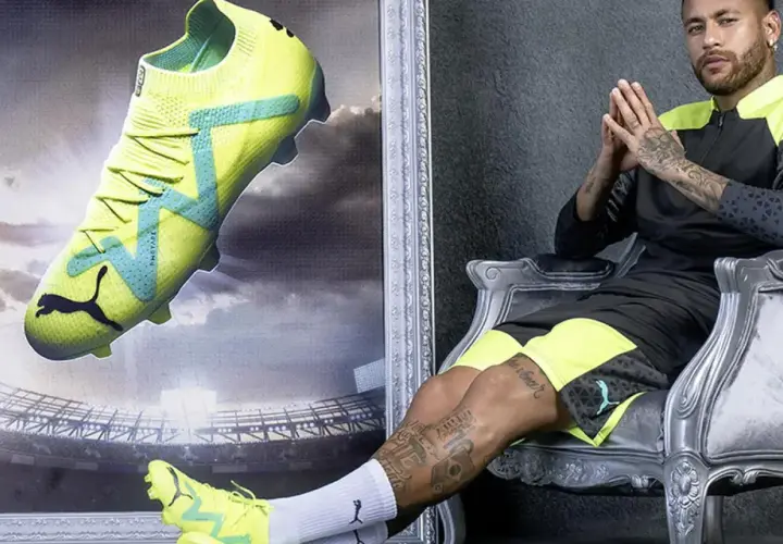 Neymar w neonowych butach piłkarskich Puma, idealnych na sztuczną trawę, siedzi na tronie.