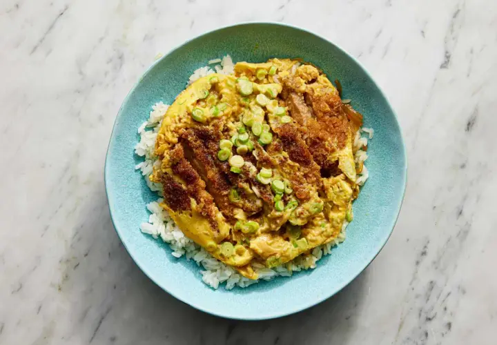 A delicious katsu donburi recipe, featuring crispy fried pork cutlet over fluffy white rice, topped with a savory egg and green onions.