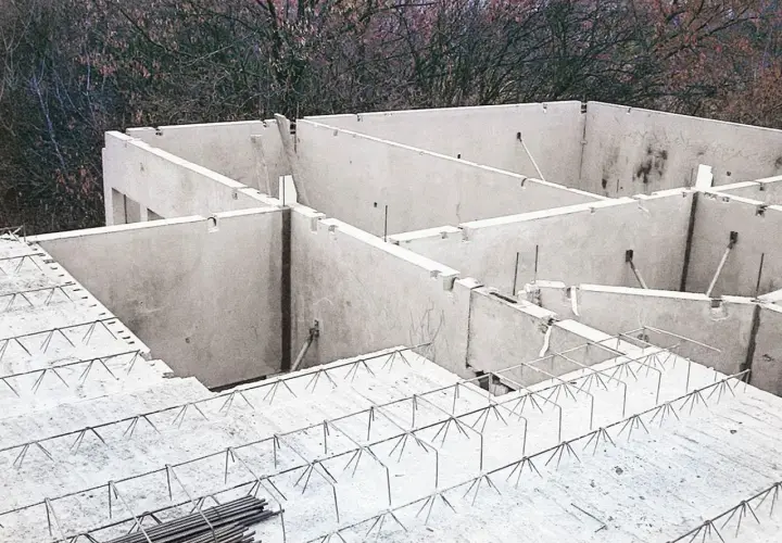 Budowa domu w toku. Widać betonowe ściany i przygotowany do wylania strop filigran z siatką zbrojeniową.