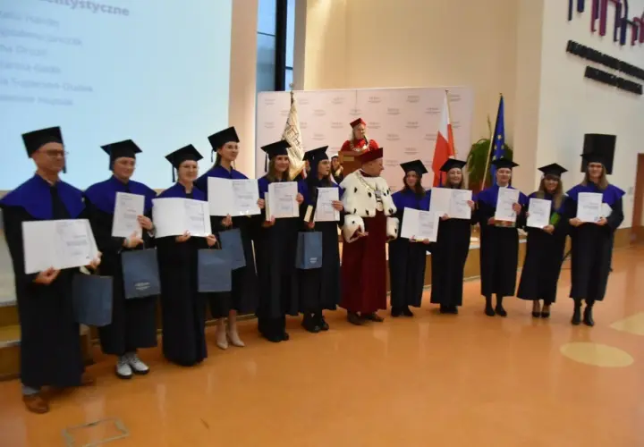 Absolwenci w togach i biretach odbierają dyplomy. Uroczystość wręczenia tytułów licencjat.
