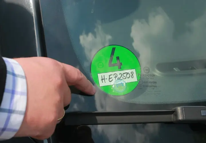 Palec wskazuje na zieloną winietę z numerem 4 i rejestracją H-EP2508, naklejoną na przedniej szybie samochodu w Niemczech.