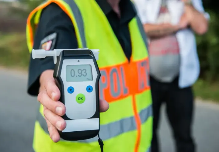 Policjant pokazuje alkomat z wynikiem 0.93 promila. To przypomnienie o **limicie alkoholu w Polsce** i odpowiedzialności za kierownicą.