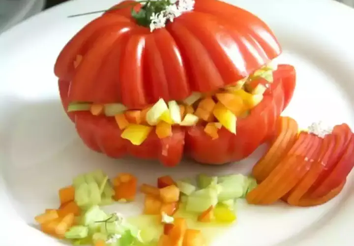 Un tomate cœur de bœuf farci de légumes croquants, servi avec des quartiers de tomate et une vinaigrette légère. Un délice estival !