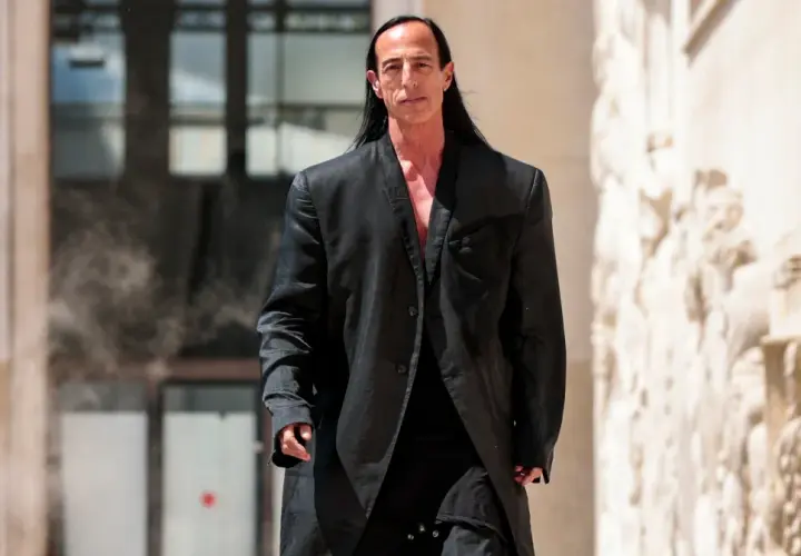 Rick Owens, w charakterystycznym czarnym płaszczu, idzie pewnym krokiem.