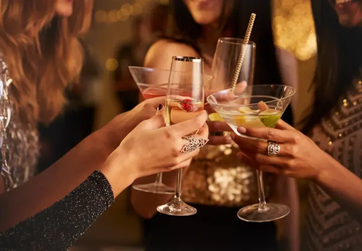 Brindis de mujeres con copas de cóctel en una celebración. La barra libre de la boda promete diversión y glamour.