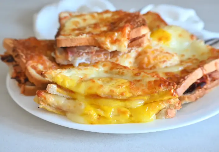 Toast filanti e dorati, preparati nella friggitrice ad aria, con formaggio fuso e un uovo.