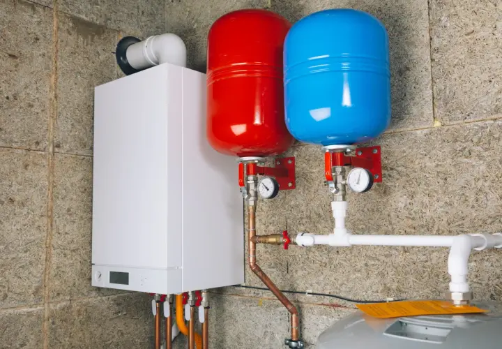 Nowoczesny biały kocioł gazowy z dwoma zbiornikami przeponowymi (czerwonym i niebieskim) oraz instalacją hydrauliczną.