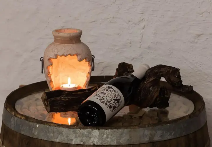 Kerzenlicht erhellt eine Flasche Wein, die auf einem Holzstück liegt. Hoffentlich wurde kein schlechten wein getrunken.