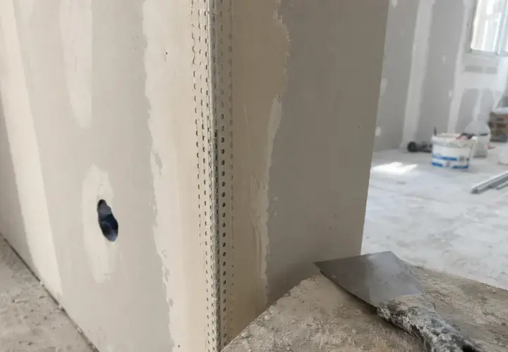 Angoli in cartongesso pronti per la stuccatura. Un angolo è rinforzato con nastro metallico, mentre l'altro è già parzialmente stuccato.