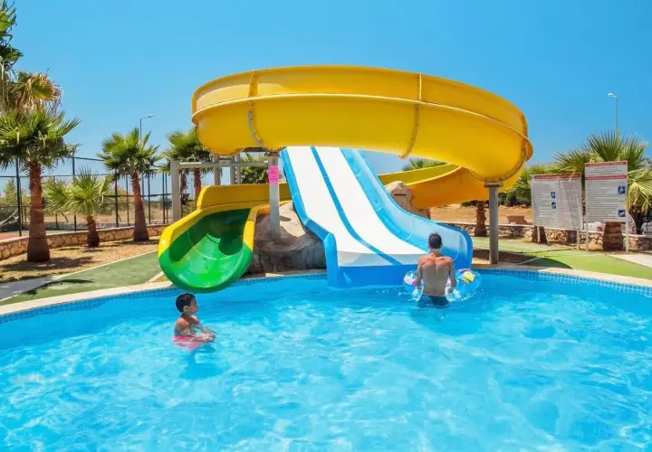 Dzieci bawią się w basenie przy zjeżdżalniach wodnych w **garden of sun spa & wellness**.