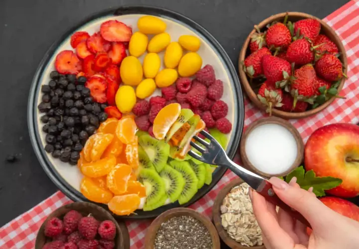 Kolorowy talerz z owocami: truskawki, jagody, maliny, mandarynki, kiwi, żółte owoce. Idealny jadłospis na dieta owocowa.