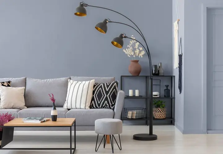 Nowoczesny salon z szarymi ścianami, wygodną sofą i designerską lampą łukową.