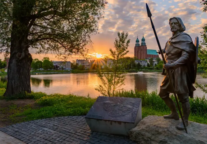 Pomnik wojownika na tle jeziora i katedry. Wschód słońca nad Gnieznem, pierwszą stolicą Polski.
