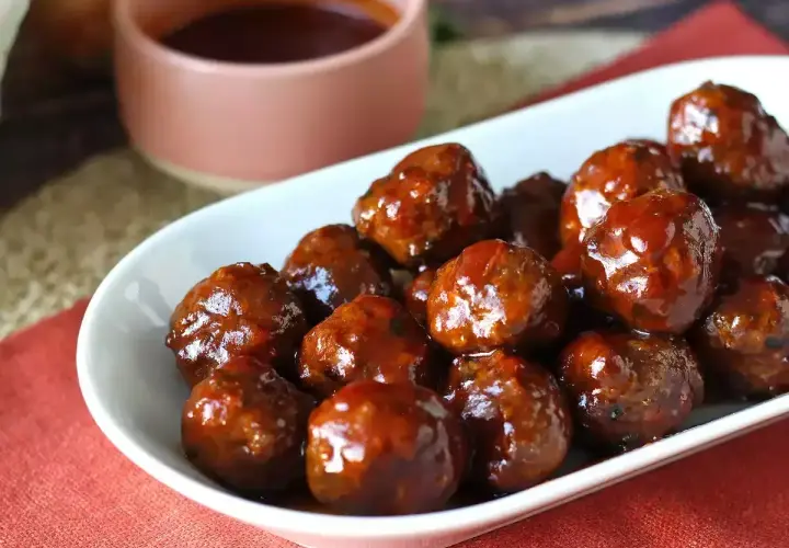 Un plat de boulettes de viande barbecue, brillantes et appétissantes, baignant dans une sauce sucrée. Parfaites pour un apéritif ou un repas convivial.