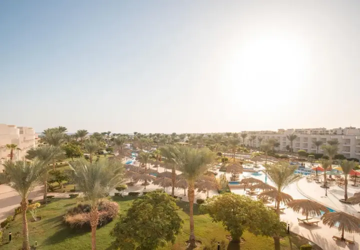 Słoneczny dzień w kurorcie Long Beach Resort Hurghada. Palmy, baseny i leżaki pod strzechą zapraszają do relaksu.