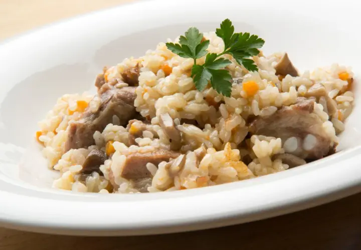 Delicioso arroz con champiñones y trozos de carne, adornado con perejil fresco.