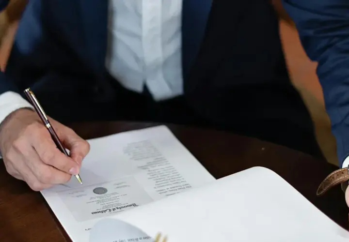 Persona firma un contrato laboral con un bolígrafo de oro.