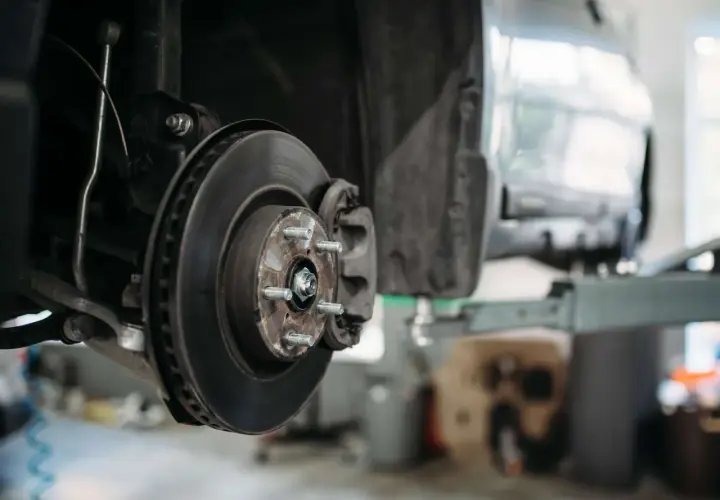 Detailaufnahme einer Autobremsanlage: Bremsscheibe, Bremssattel und Radnabe. So sieht eine Bremse aus, wenn sie für Wartungsarbeiten demontiert ist.