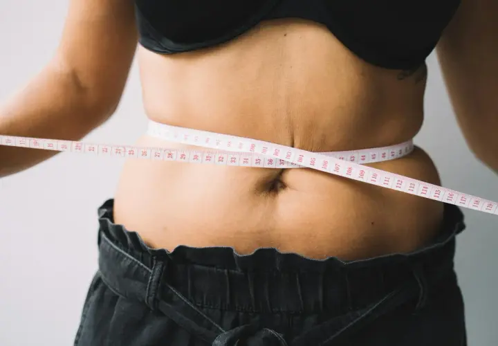 Kobieta mierzy talię centymetrem. Czy to początek drogi, jak szybko schudnąć 20 kg?