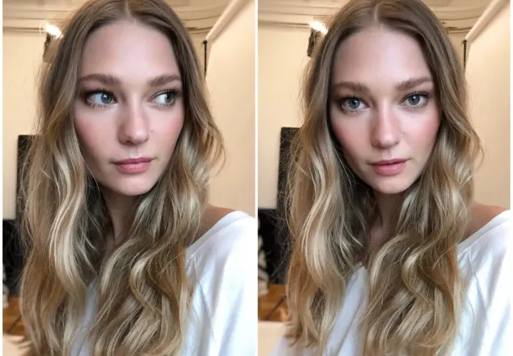 En kvinna med blont, vågigt hår och en subtil, naturlig makeup som framhäver hennes blå ögon och rosiga kinder.