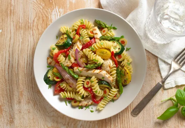Sabrosa ensalada de pasta con pollo a la parrilla, calabacín, pimientos rojos, espárragos y aceitunas.