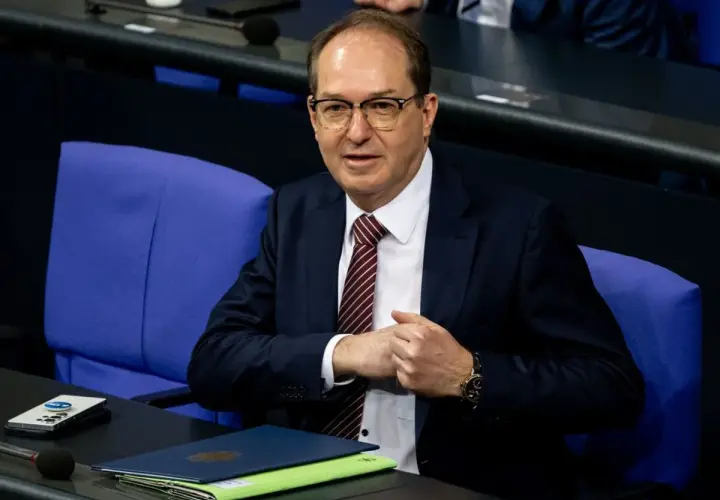 Ein Mann mit Brille und Krawatte sitzt im Bundestag. Er wirkt nachdenklich, während er seine Hände faltet. Viele Bundestagsabgeordnete sind Beamte.