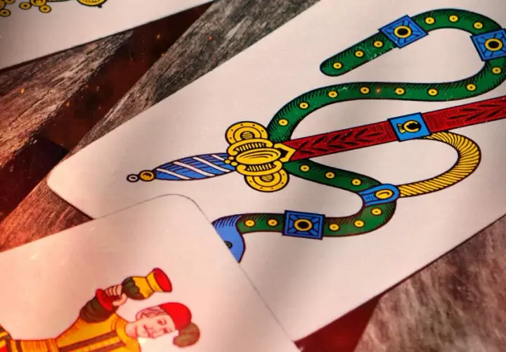 Carte da gioco napoletane, tra cui il sette di spade e un personaggio. Immagina come si gioca a cucù con queste carte!