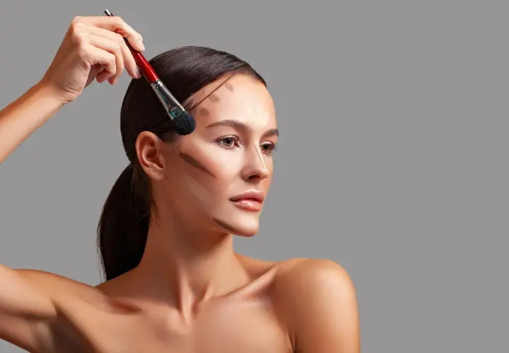 Modelka z pociągnięciami bronzera na twarzy, pokazującymi, do czego służy bronzer: podkreślenia rysów i nadania głębi.