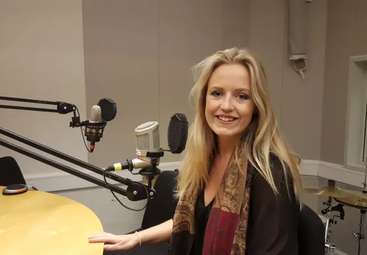 Maria Broberg ler i en radiostudio med mikrofoner och trummor i bakgrunden.